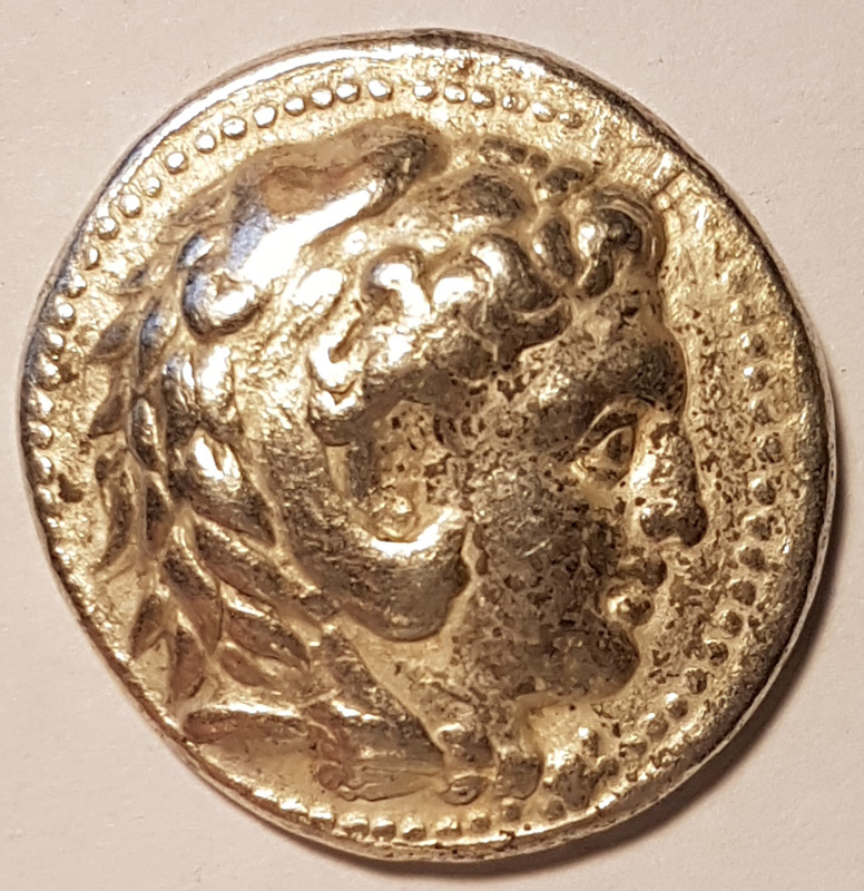 Alexander the Great as Heracles in his lion's head is shown on the obverse side of the coin. 