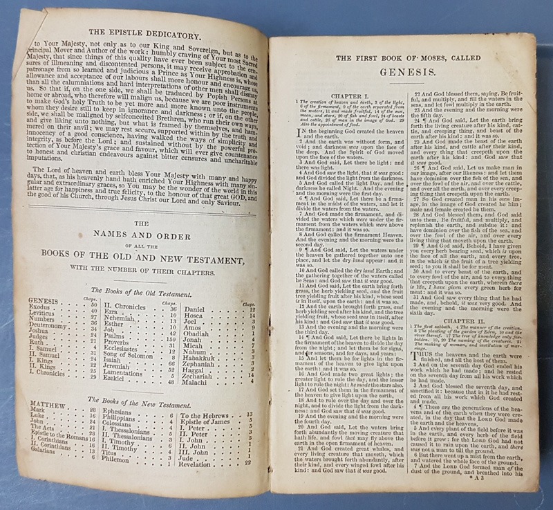 Bible open at The Epistle Dedicatory, Names & Orders of the Books of the Old and New Testament and to the right The First Book of Moses called Genesis Chapter 1